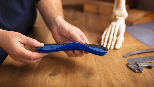 Podiatrist holding a blue soft orthotic insole in a clinic